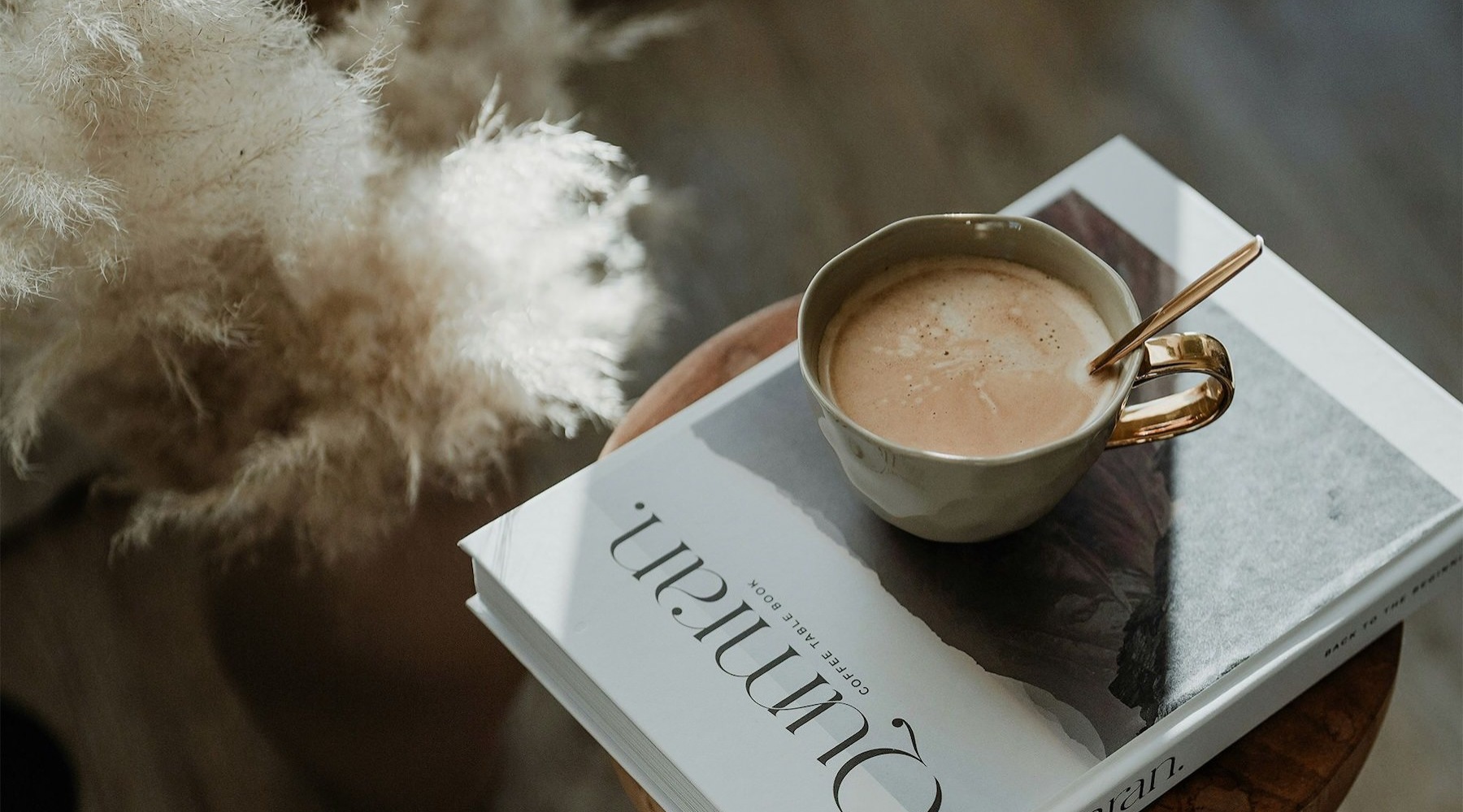 a cup of coffee on a book on a stool in a living room